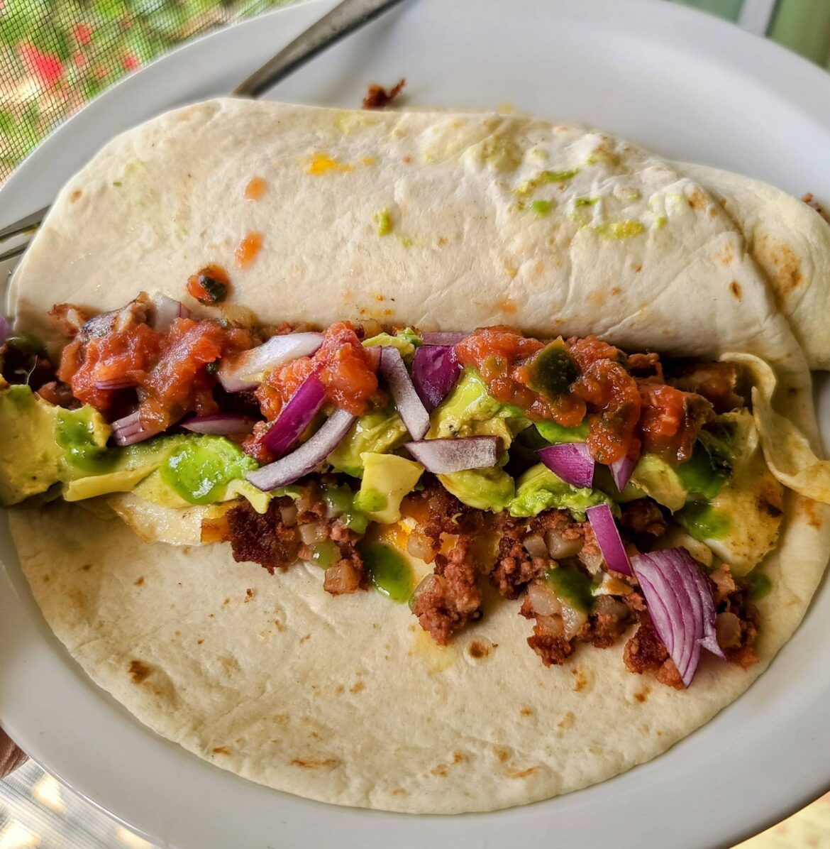 Sunday's breakfast burrito with corned beef hash, sausage, egg, avocado, red onion, salsa, and El Yucateco green habanero hot sauce