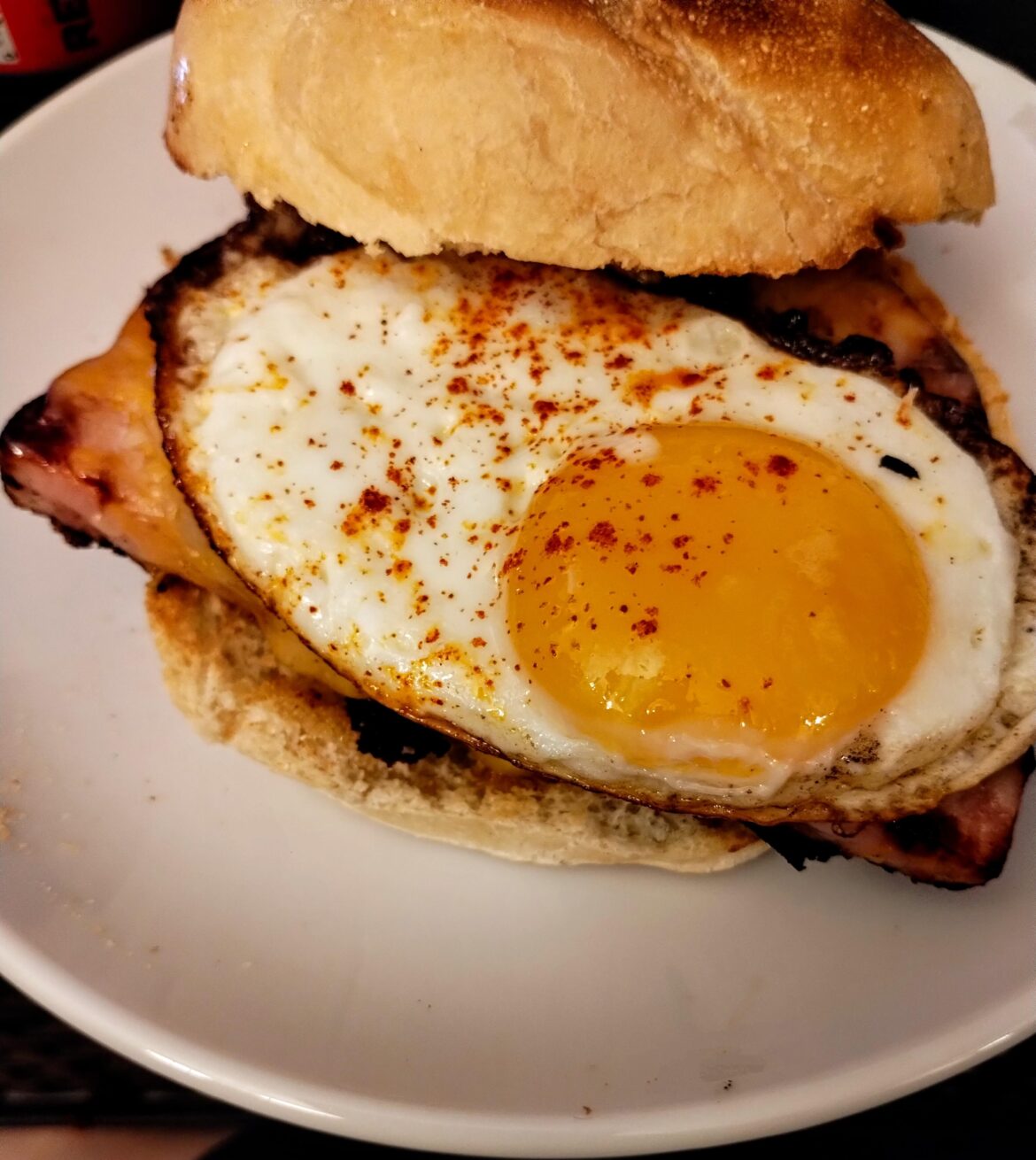 Sunny fried egg with smoked paprika on top of maple ham, cheese, and a toasted roll