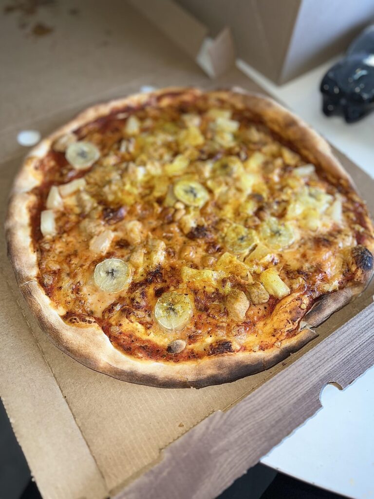 Indiana; pizza with banana, chicken, curry, pineapples and nuts. My favorite, not a crime!😄