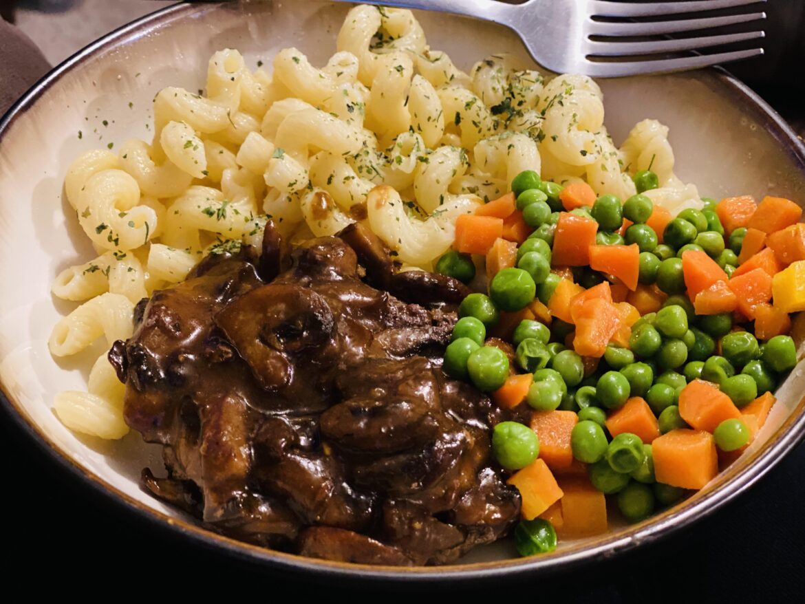 Hamburger steaks with mushroom gravy, buttered pasta, and peas & carrots.