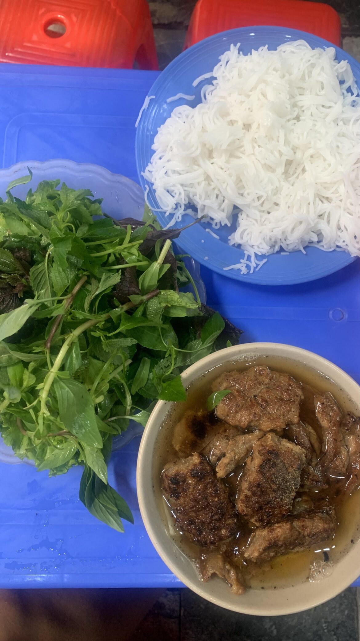 Bun cha, a Vietnamese dish of grilled pork and noodle. Originated from Hanoi, Vietnam. Served with grilled fatty pork over a plate of white rice noodle and herbs with a side dish of dipping sauce.