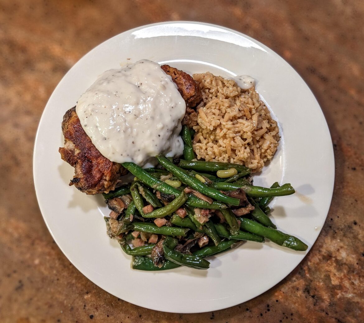 Pork chop with country gravy, green beans, and rice pilaf