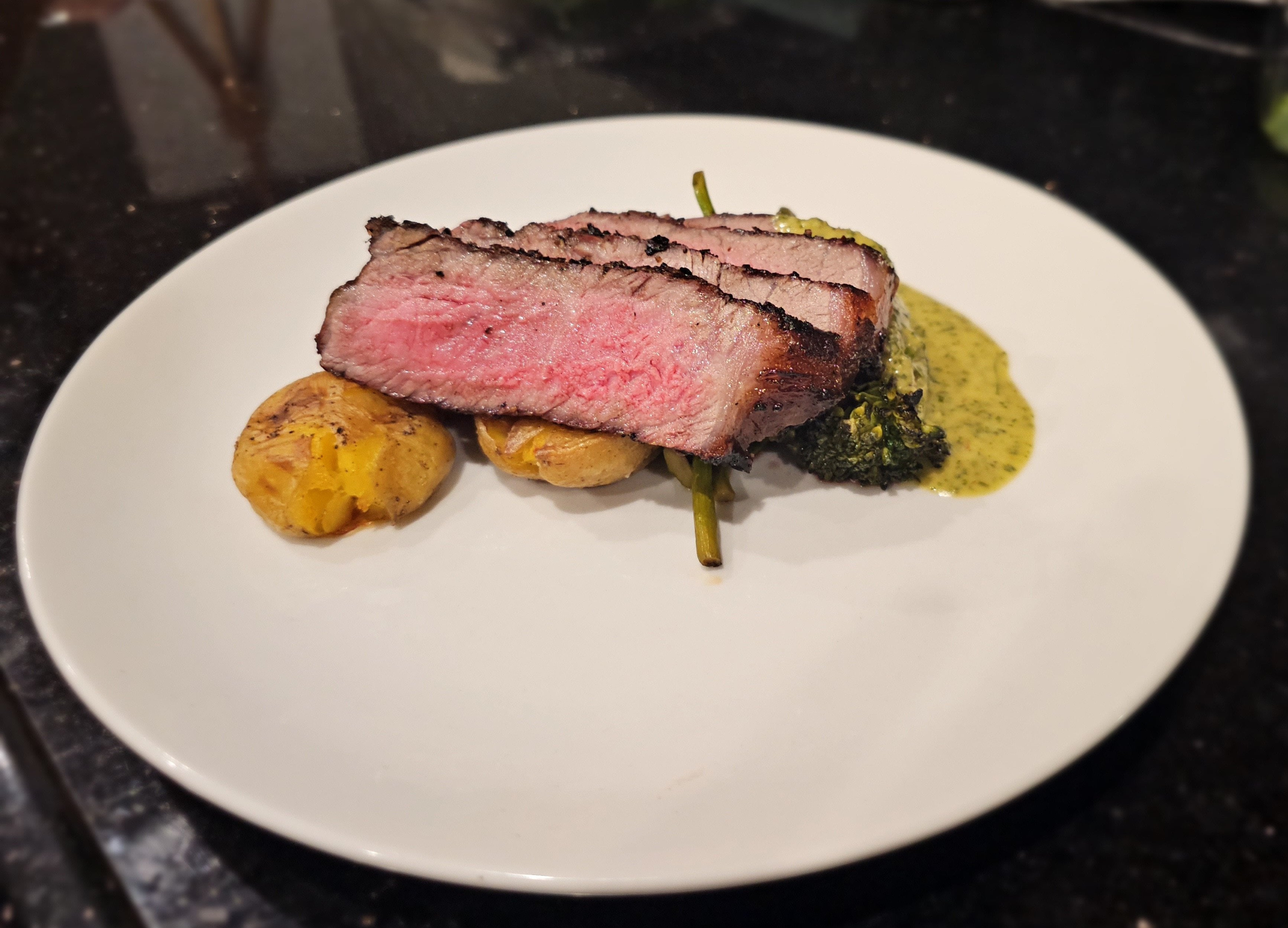 New York Strip with crispy potatoes, charred broccolini, and herb