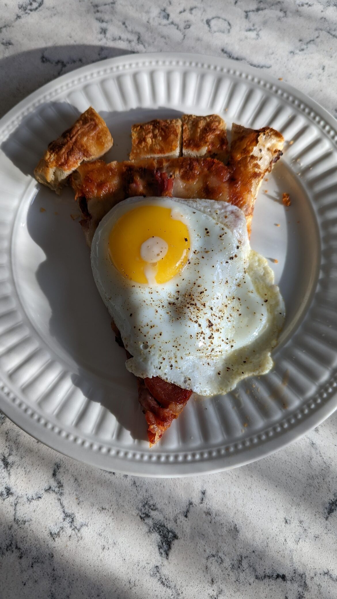Sunny side up egg over left over meat lovers pizza.