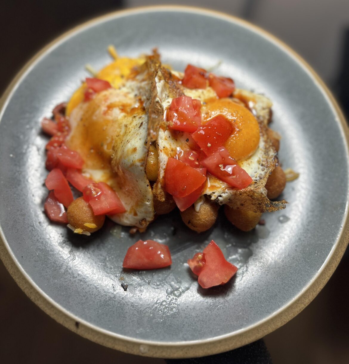 Cheesy Tater Puffs. With sautéed diced onions, fry seasoning seasoned butter, spicy bacon 🥓, diced tomatoes, & two eggs on top. #brunch #itsinthebag