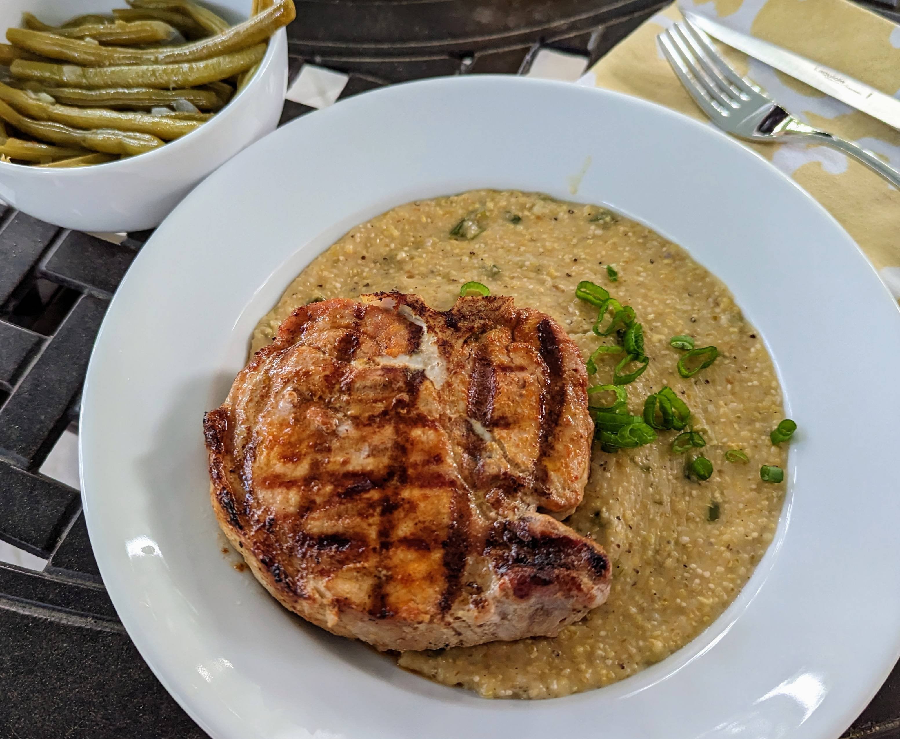 Spicy grilled Red Wattle pork chop over jalapeno cheddar grits Dining
