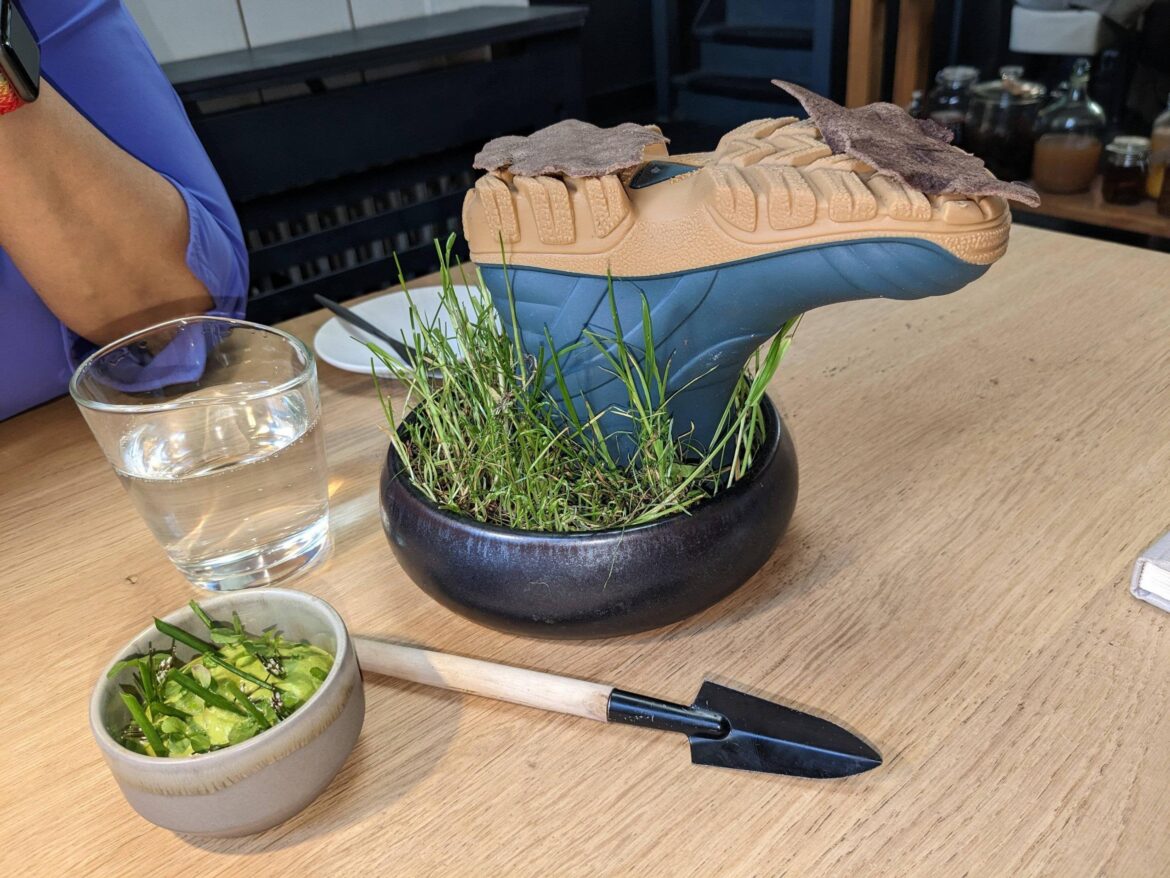 Two teff crackers served on an upside-down rubber boot stuck in grass.