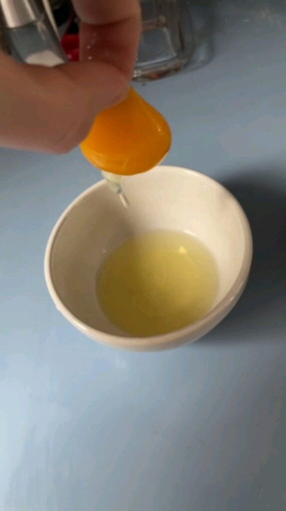 Separating egg yolk from whites with garlic rubbed fingers