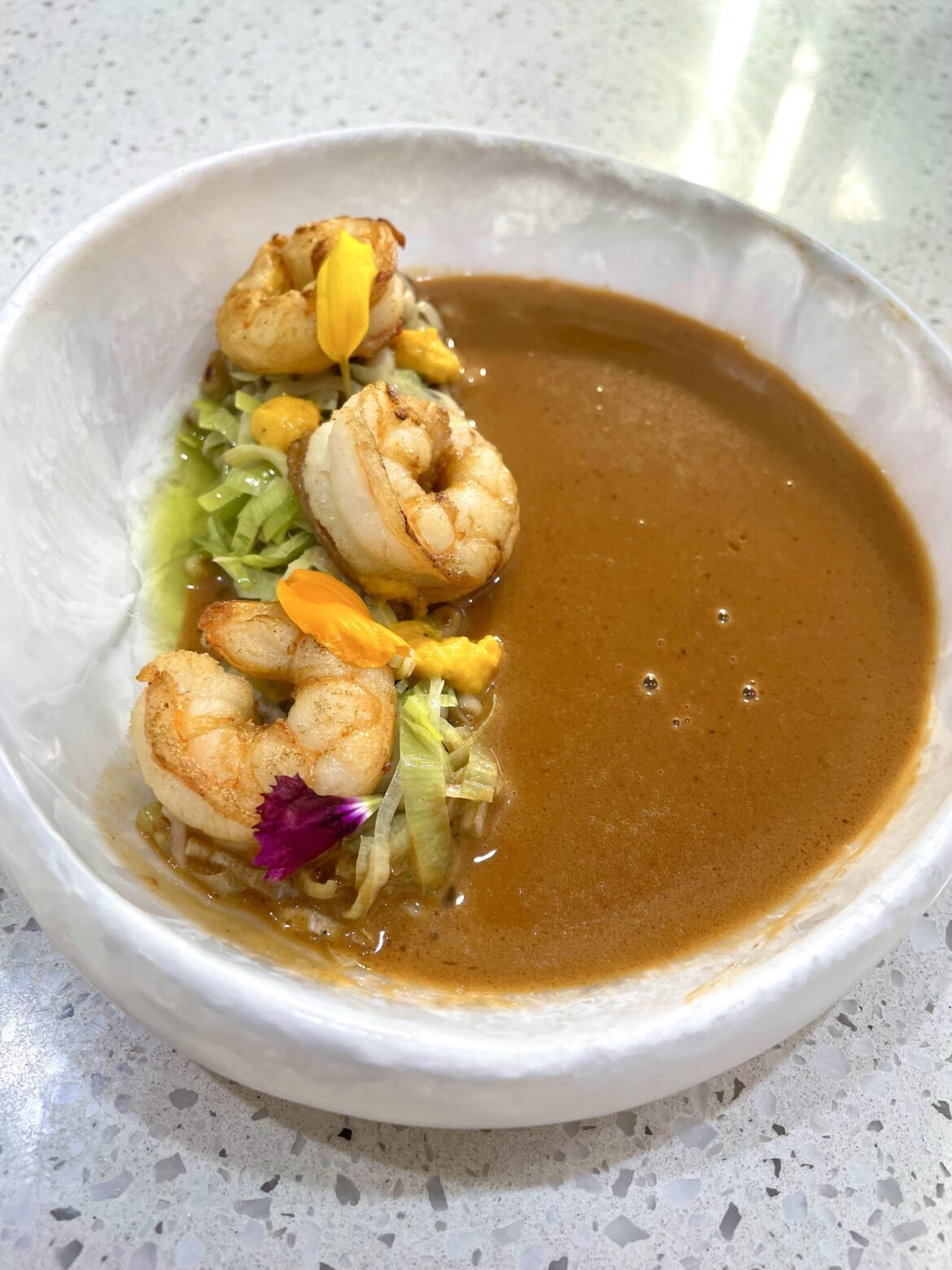 Prawn Bisque with grilled prawns, leeks and pine nuts and a drop of herb and lemon oil