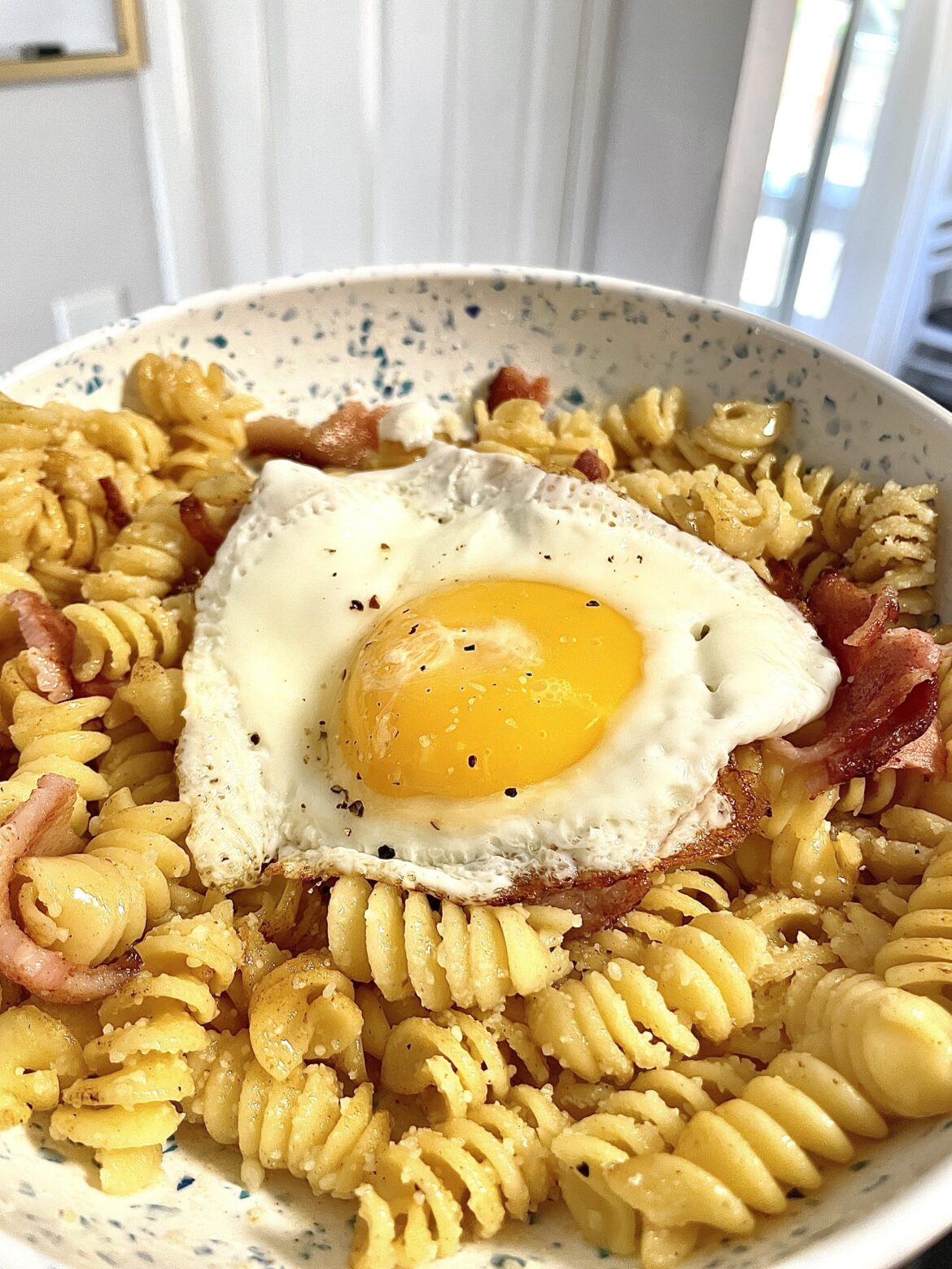 Bastardized carbonara, or breakfast pasta! Buttered noodles with parmesan, bacon, and sunny side up