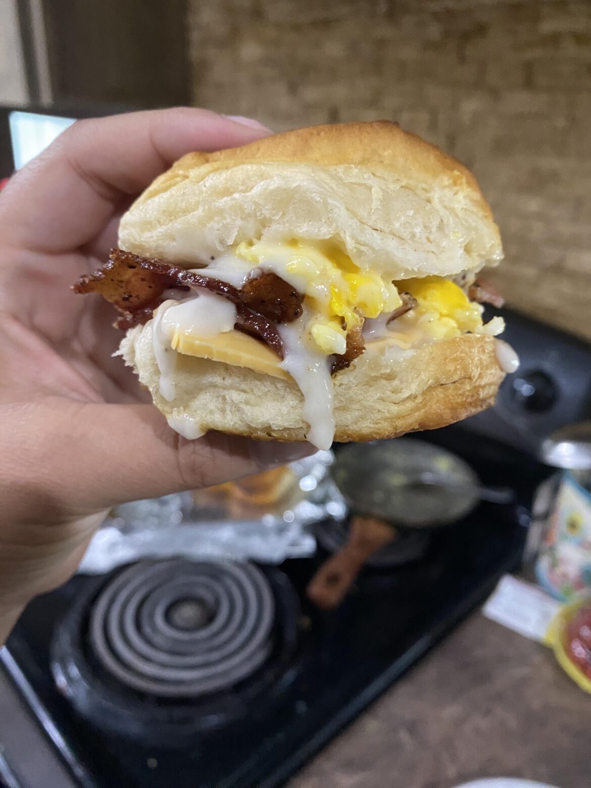 Biscuit and gravy breakfast sandwich [homemade] with bacon and fresh eggs