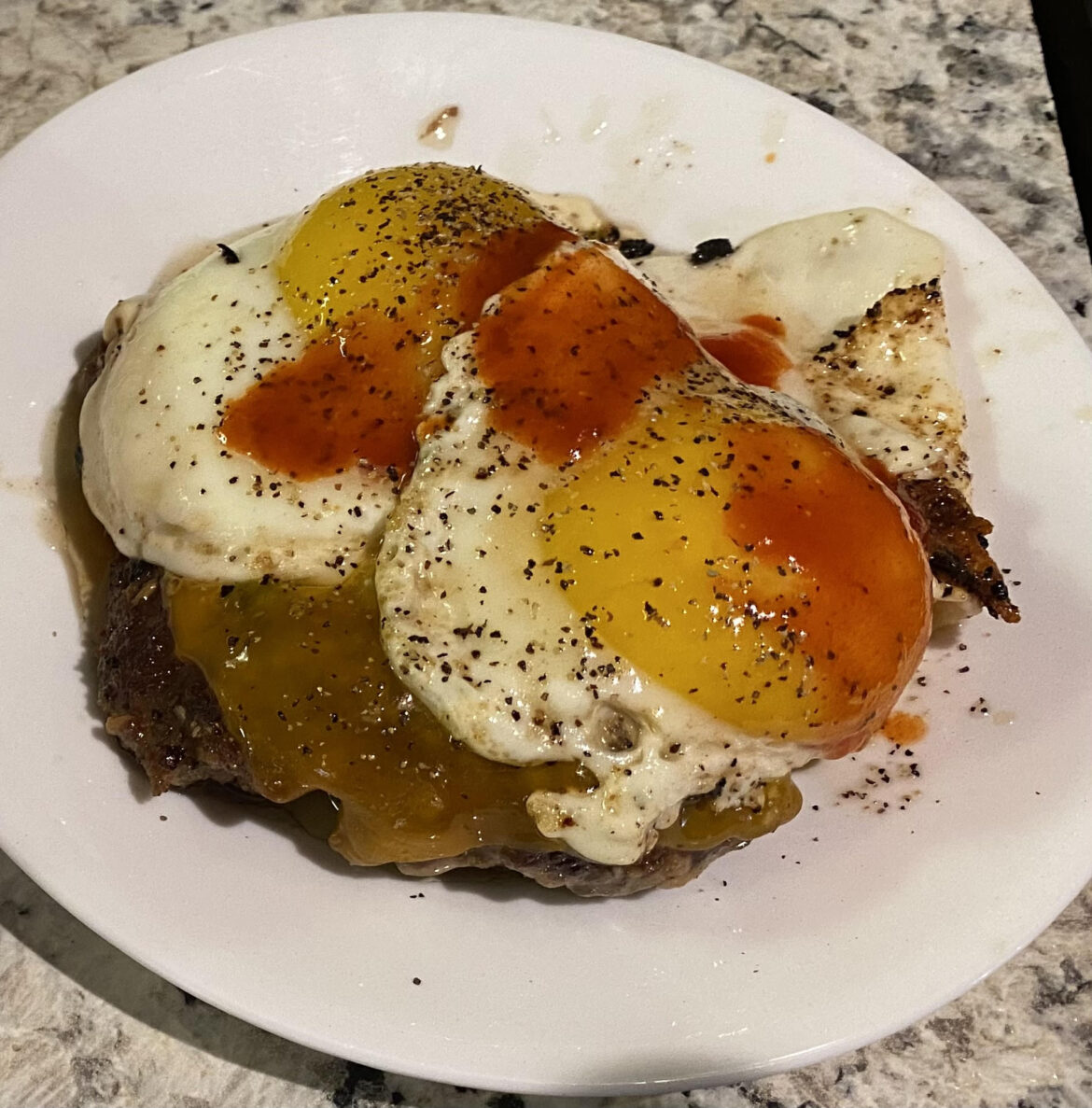 Sloppy looking, but delicious. Eggs over burger patty with cheddar and hot sauce