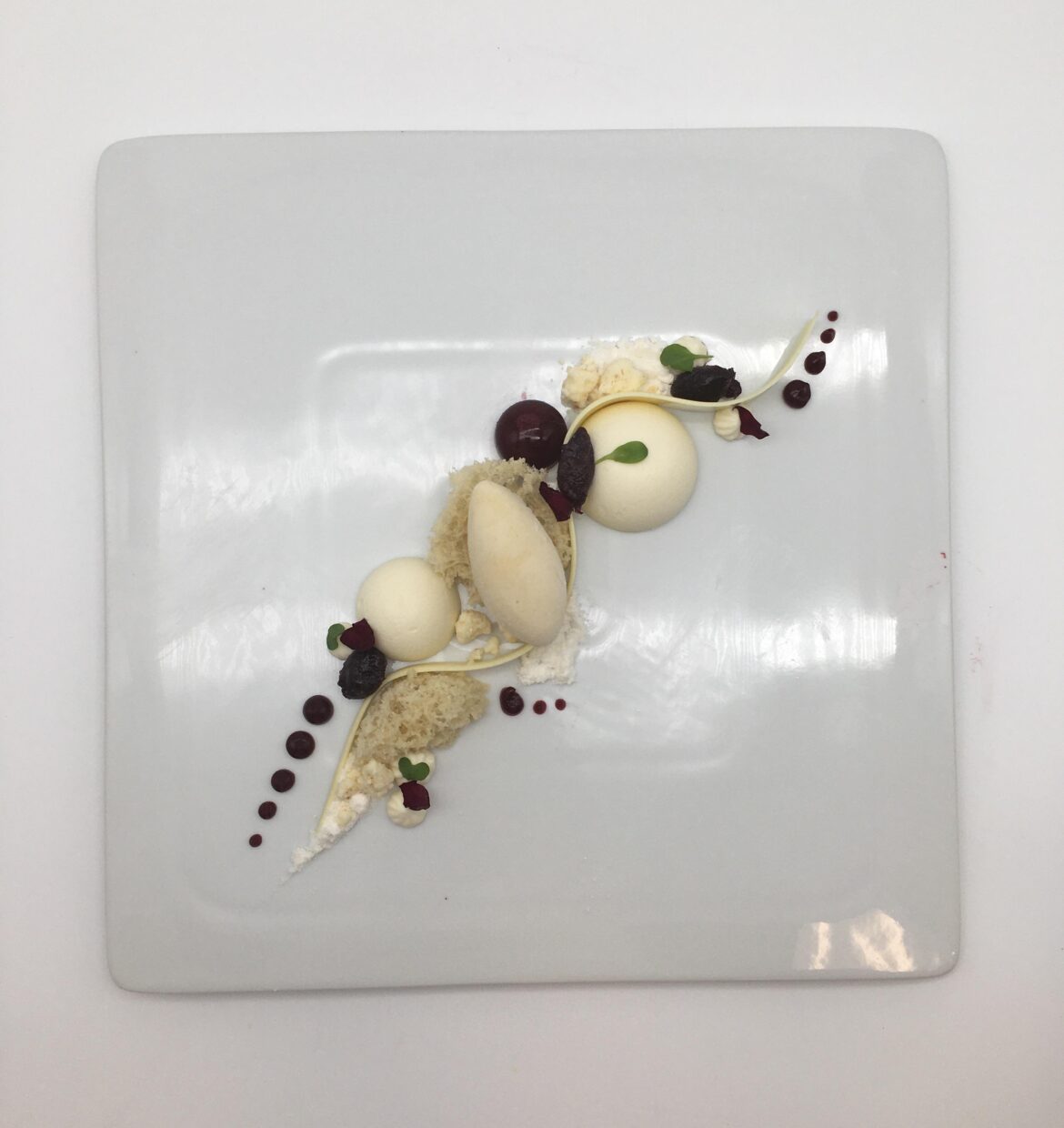 “White Chocolate Experiment” with white chocolate mousse spheres, yuzu sorbet, micro sponge cake, and black cherry fruit gel.
