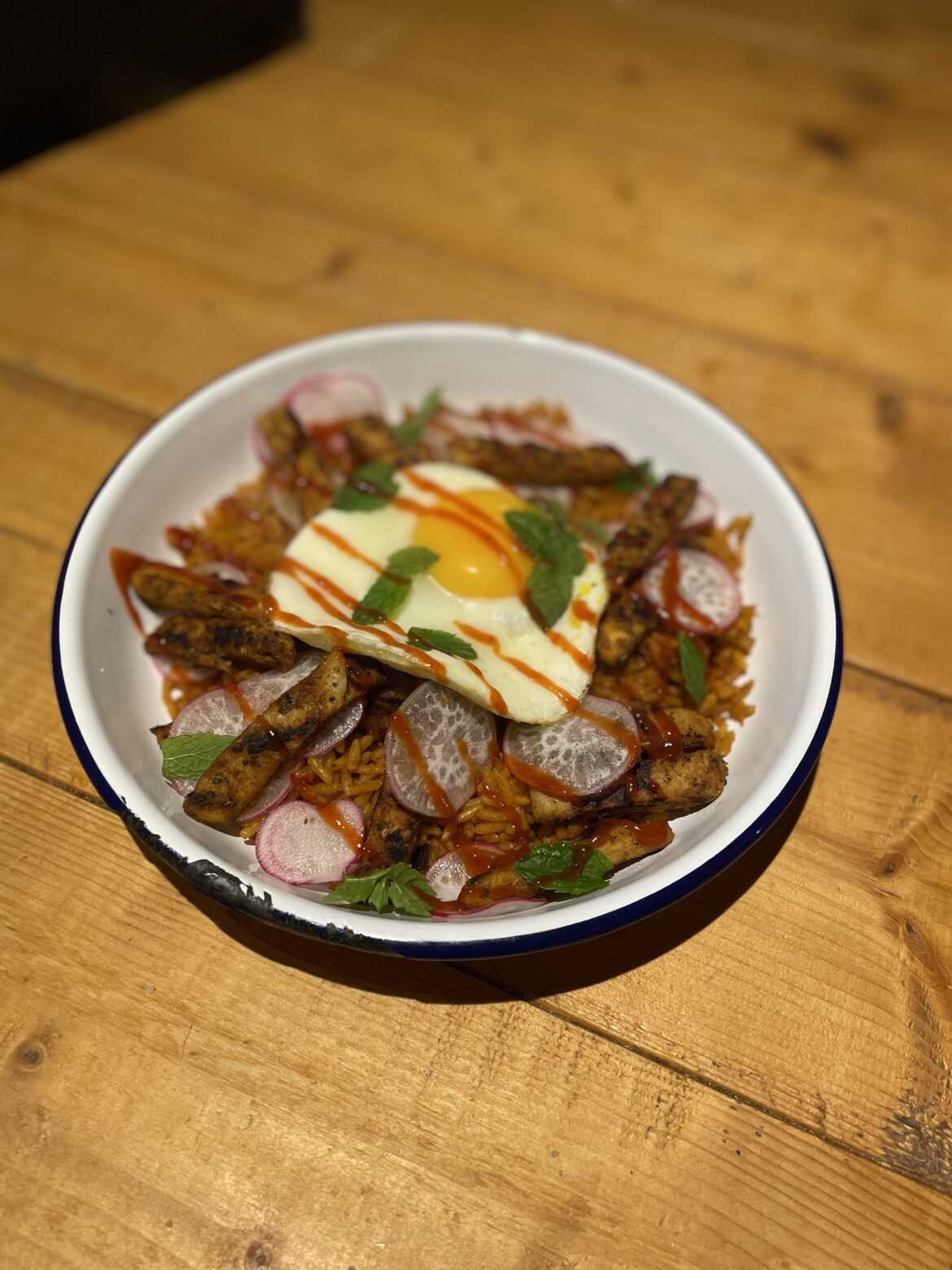 Goan Style Curry Rice, Plant Based Kebab Pieces, with Radish Shavings, Sriracha Sauce, Fresh Mint Leaves. Topped with a Fried Egg!