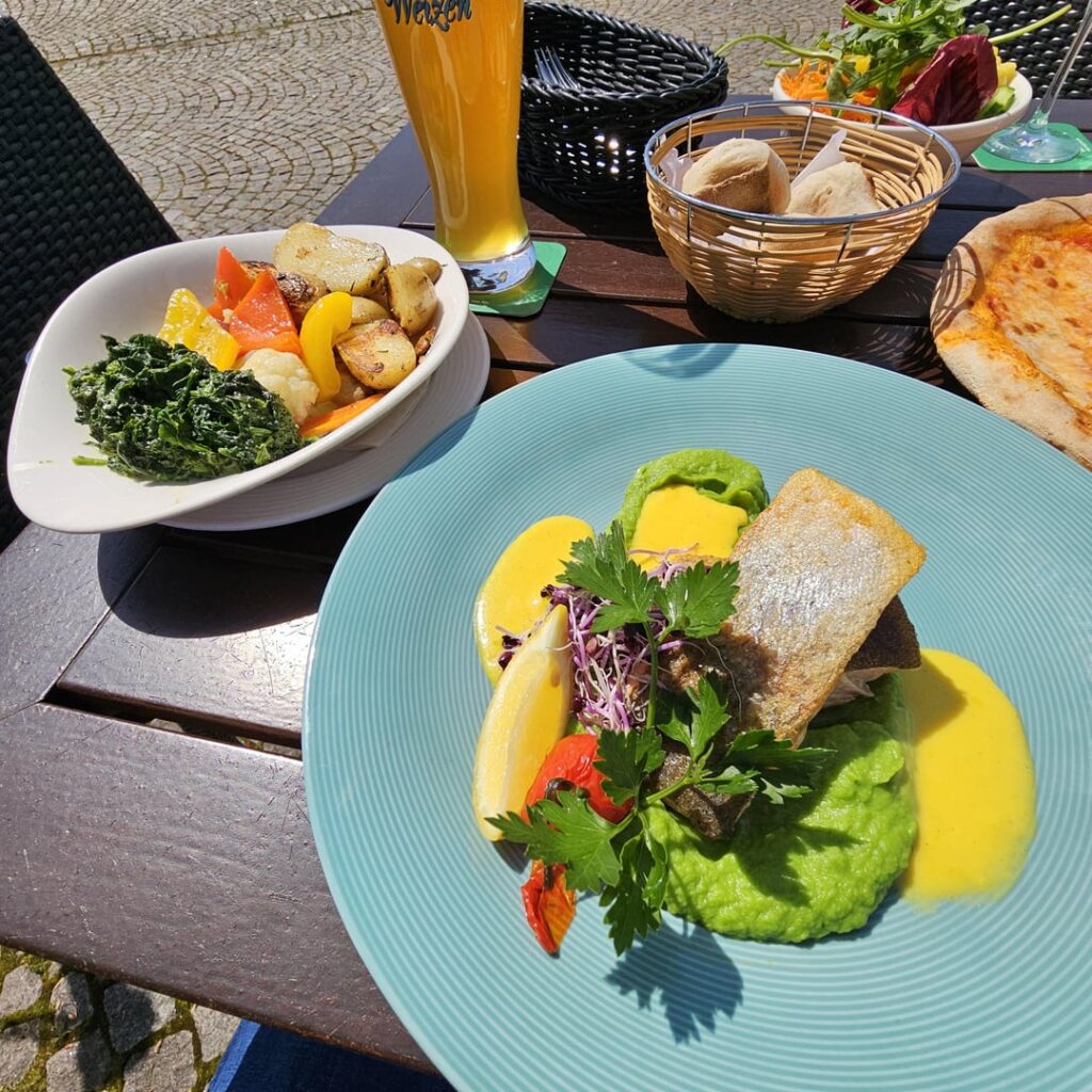 Grilled salmon trout fillet on pea puree and saffron sauce, with rosemary potatoes, seasonal vegetables and creamed spinach (along with a wheat beer)