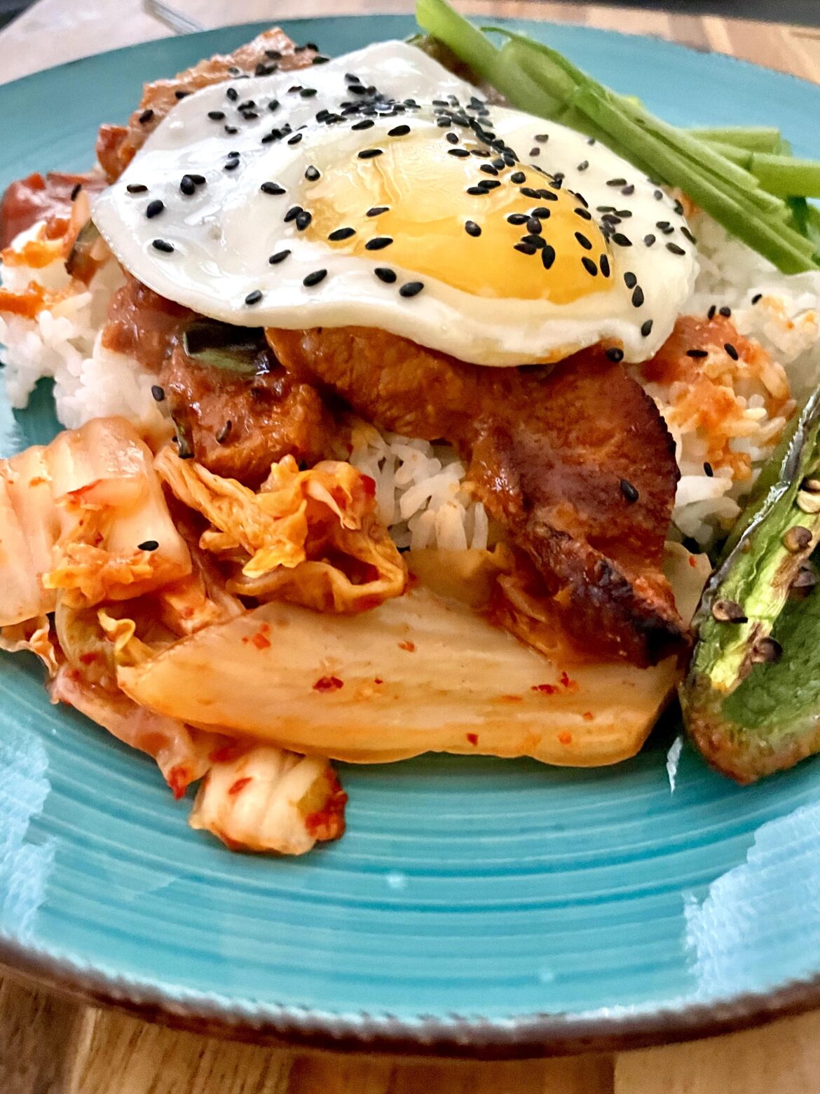 Korean spicy pork, steamed rice, kimchi, green onion, black sesame and An Egg On It.