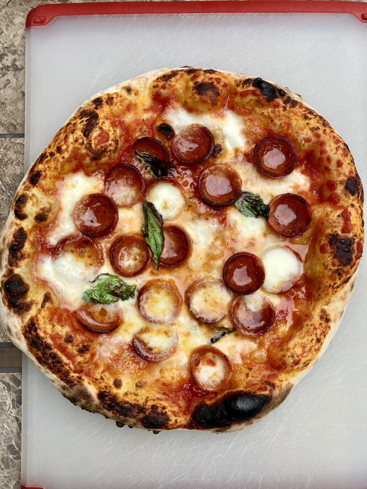 Sourdough pizza with fancy pepperoni, basil, and a hot honey drizzle. Baked in my Roccbox