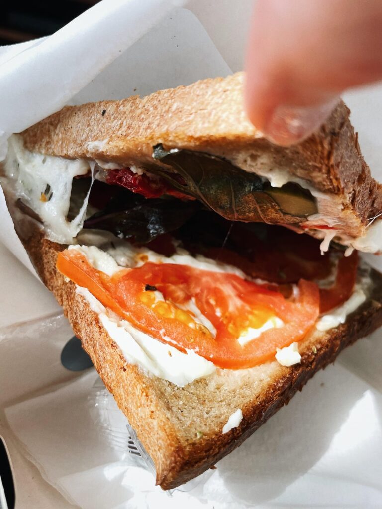 Delicious toast with feta cheese, tomatoes, purple basil, pickles and dried tomatoes for a full filling breakfast.
