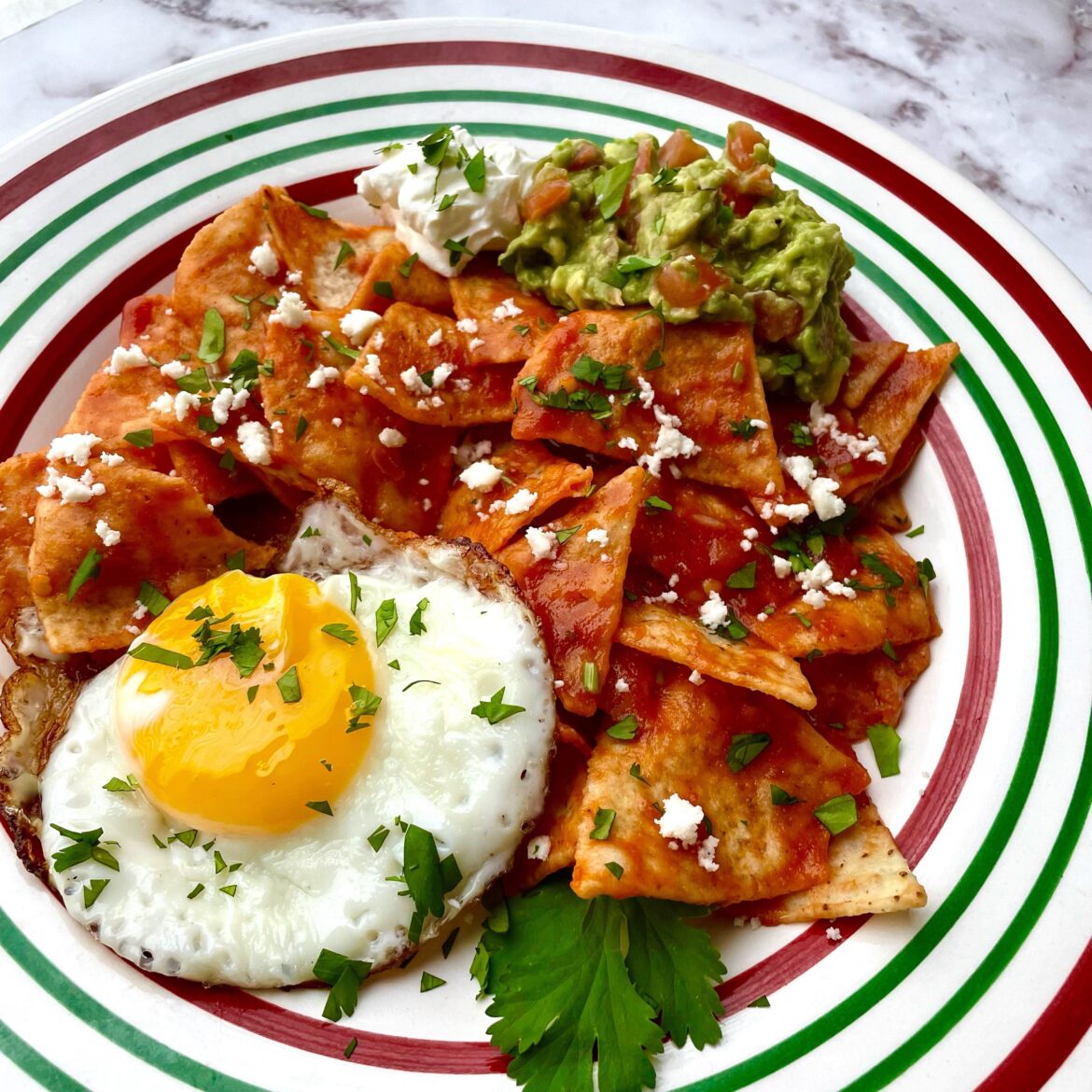 Chilaquiles with Sour Cream. Chopped Cilantro. Queso Fresco. Diced Red Onions. Guacamole. Topped with a Frizzled Egg