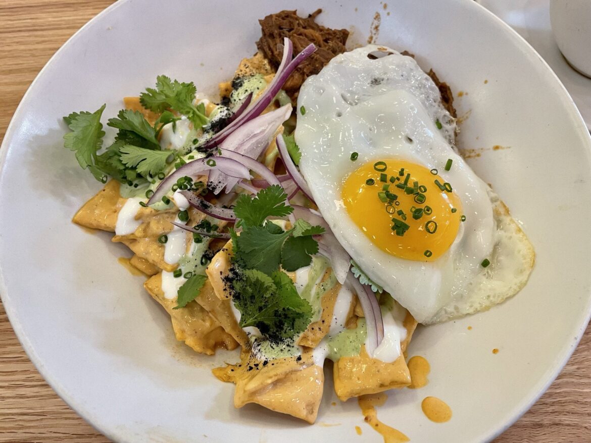 Chipotle chilaquiles with cilantro sauce, onions, barbacoa beef, and egg on top