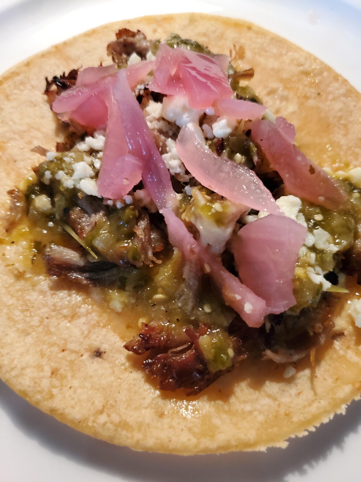 Tacos de Caritas with homemade salsa verde, cotija cheese and Yucatán style pickled red onions pickled with grapefruit, orange and lime juice.