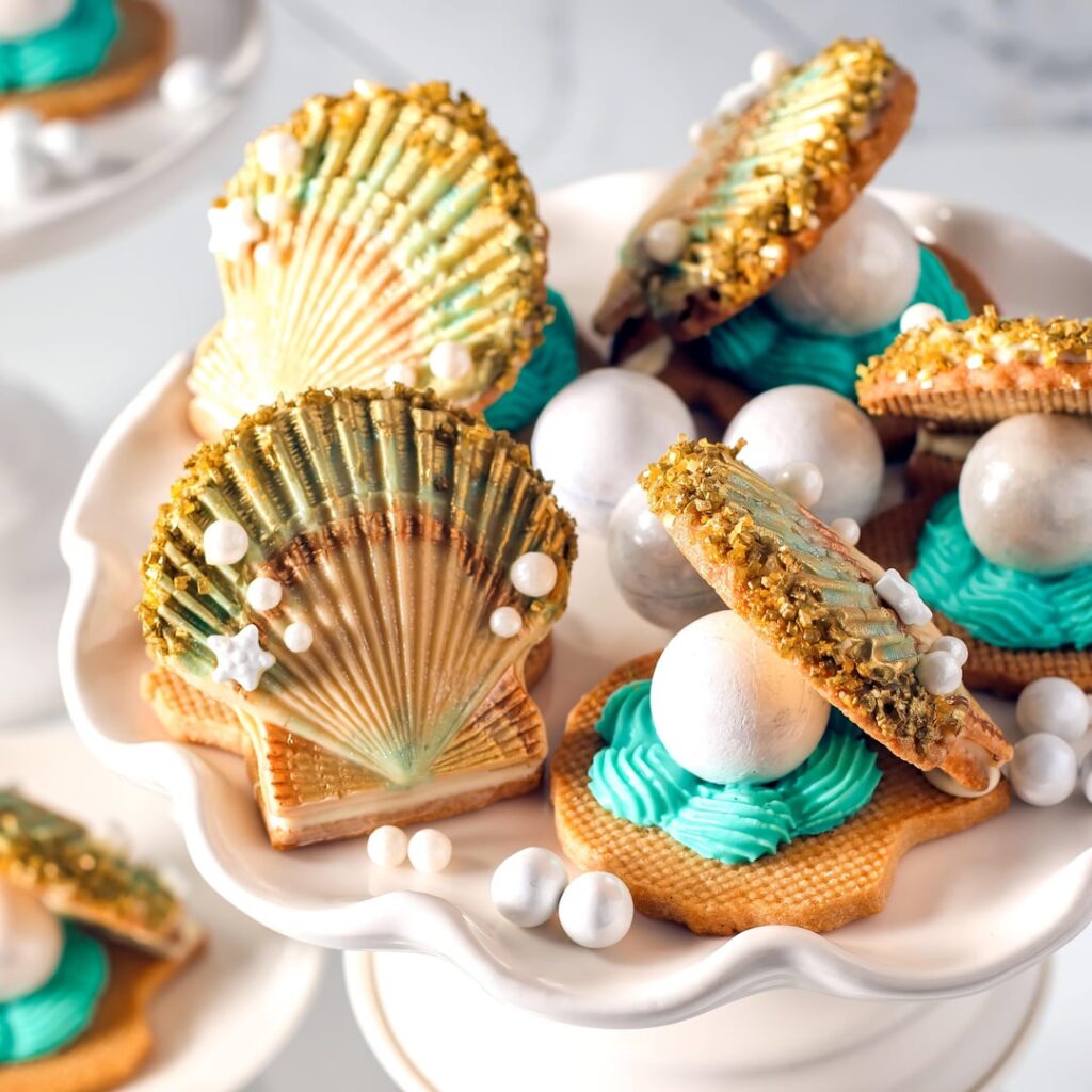 I made shortbread clamshell cookies decorated with white chocolate. The pearls are bonbons filled with malted milk chocolate ganache.