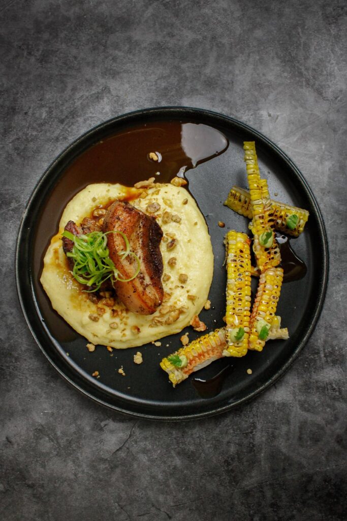 Pork belly on polenta w. Toasted walnut, scallion tops & brown ale & stock reduction / Butter poached sweet corn doused in chili infused olive oil, toped with a cilantro/feta cheese crema
