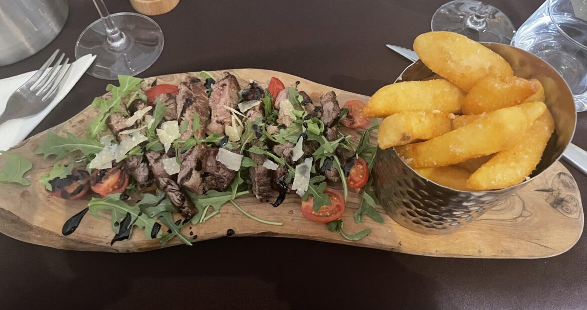 steak with rocket tomato and truffle potatoes on a bit of wood at an italian restaurant in London