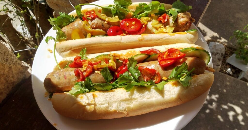 Home Made Pork Banh Mi Snausages, cucumber, cilantro, gochujang mayo, mild pickled cherry peppers on Martin's hoagie rolls