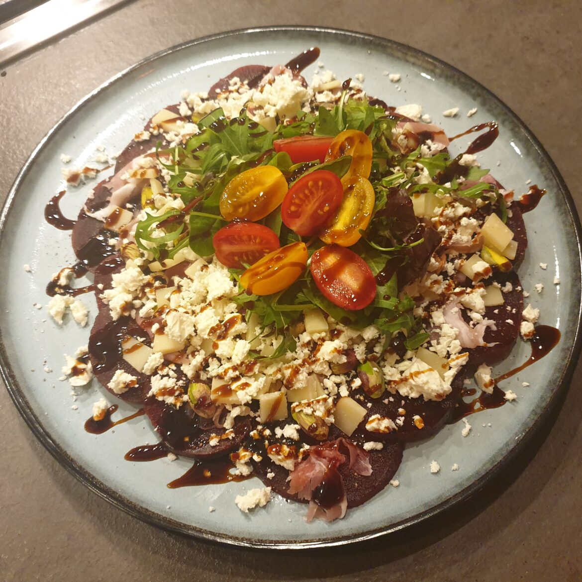 Carpaccio with pistache feta cheese crudo ham parrano cheese rockets cherry tomato and crema balsamico