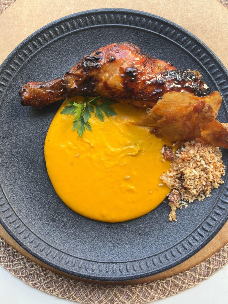 Caramelized orange chicken drumstick, acorn squash aligot, farofa (Brazilian sttufing), crispy chicken skin, parsley leaf.