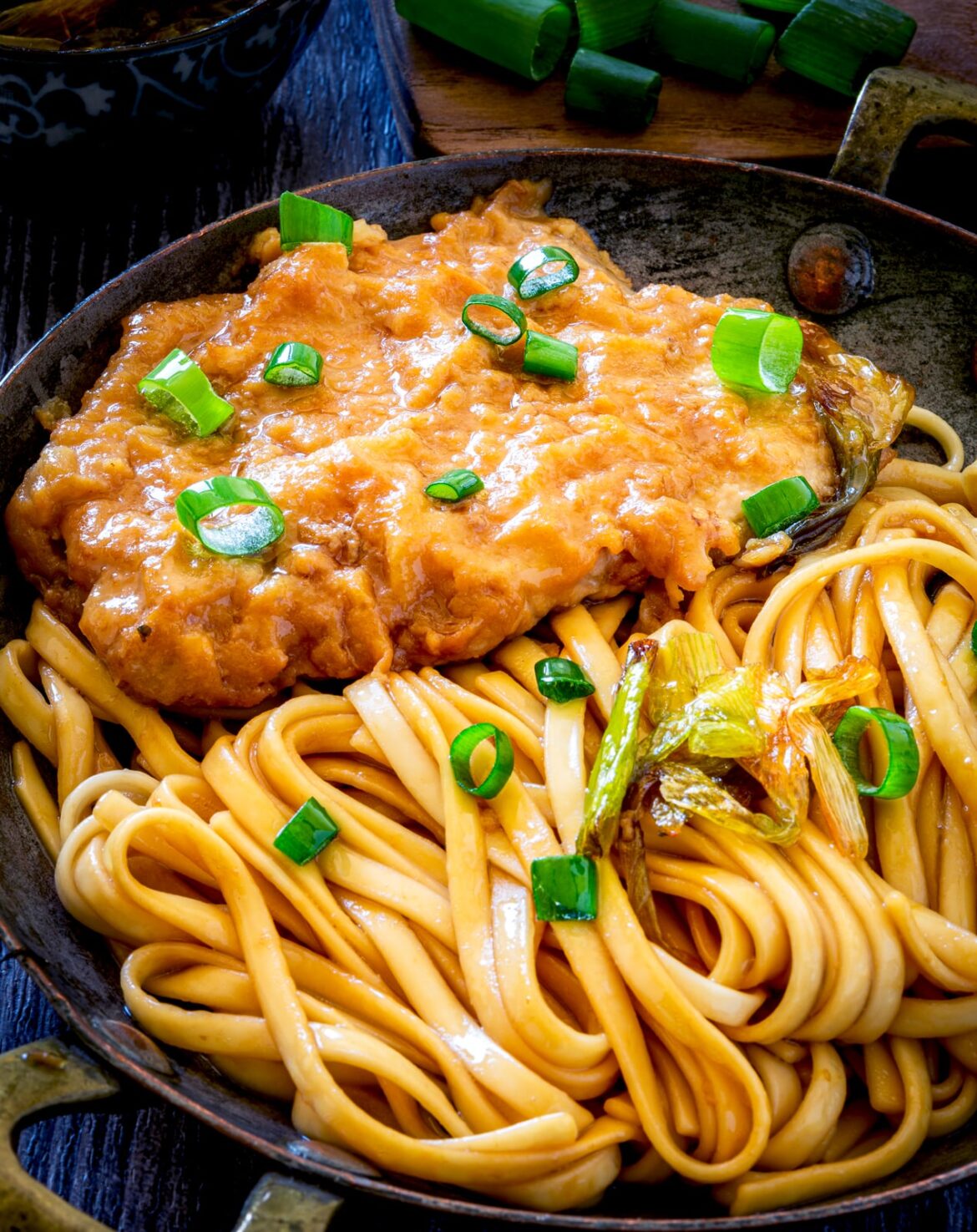 Tender pork chops infused with the flavors of spring onion, served with noodles.