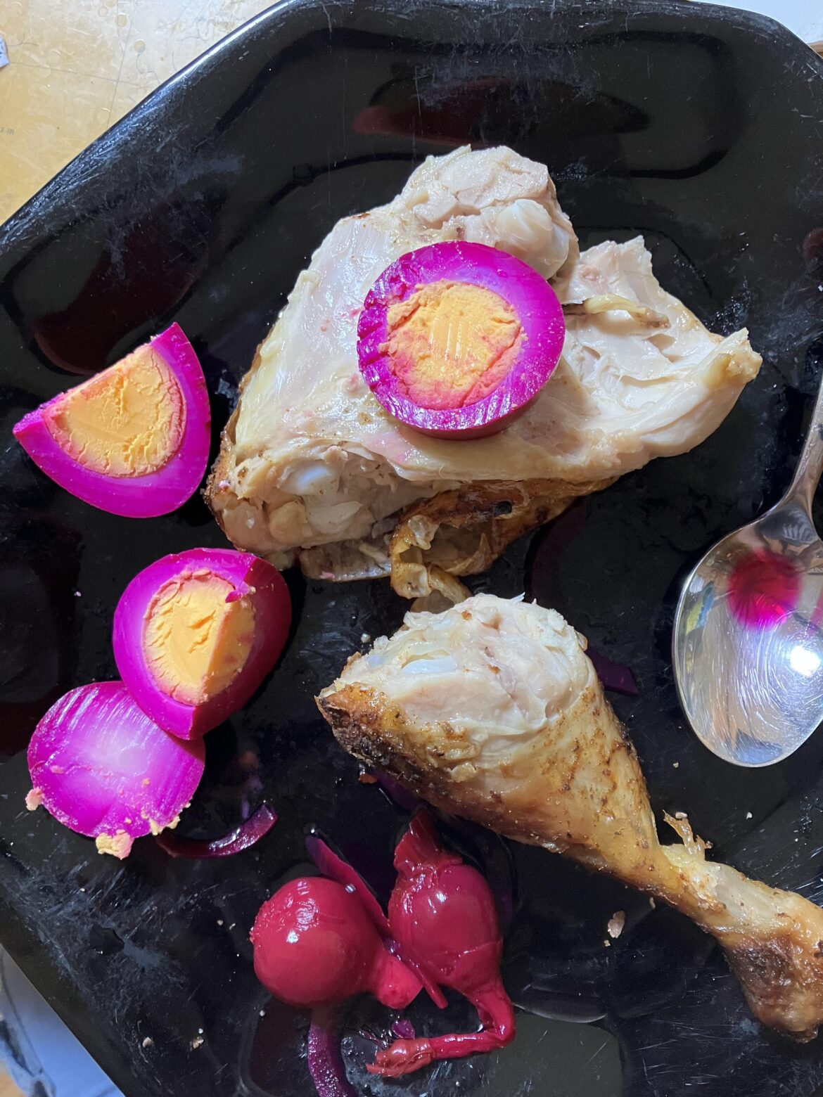 An egg pickled with baby beets sliced on a roasted chicken thigh