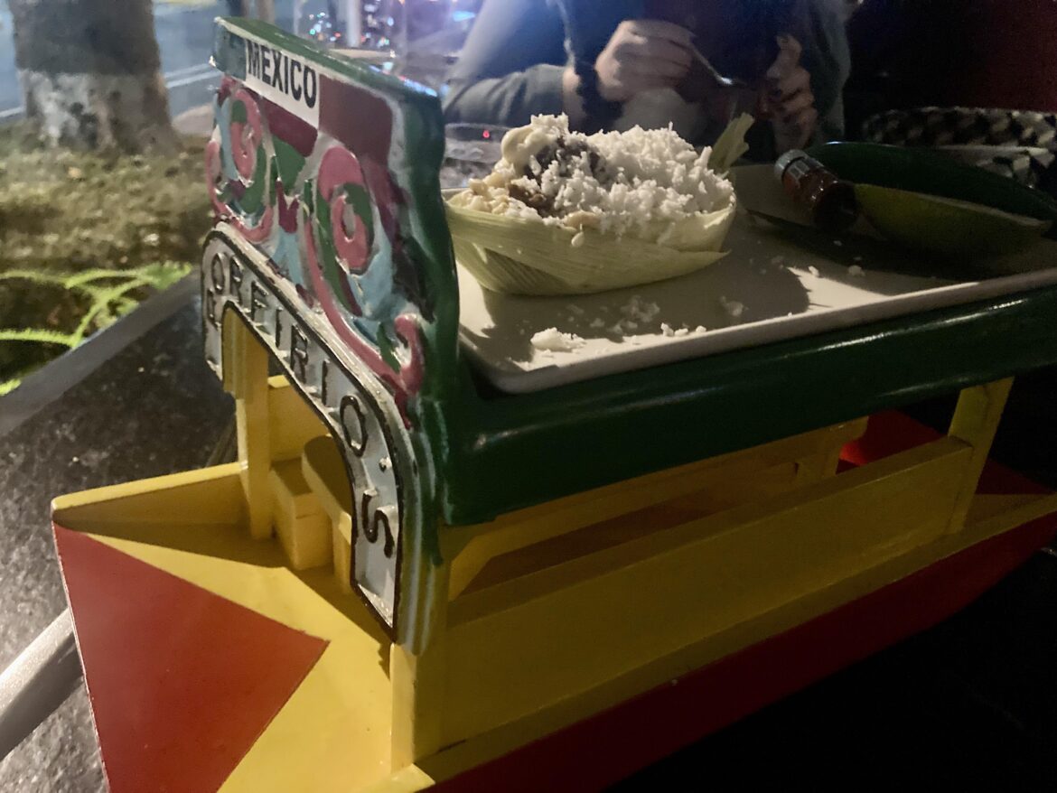 Elote in a corn husk boat on top of a mini trajinera
