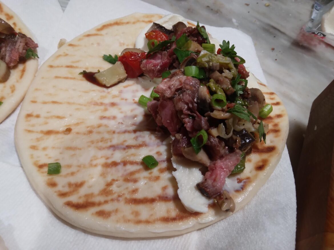 Steak,veggies,cheese, balsamic on pita bread.