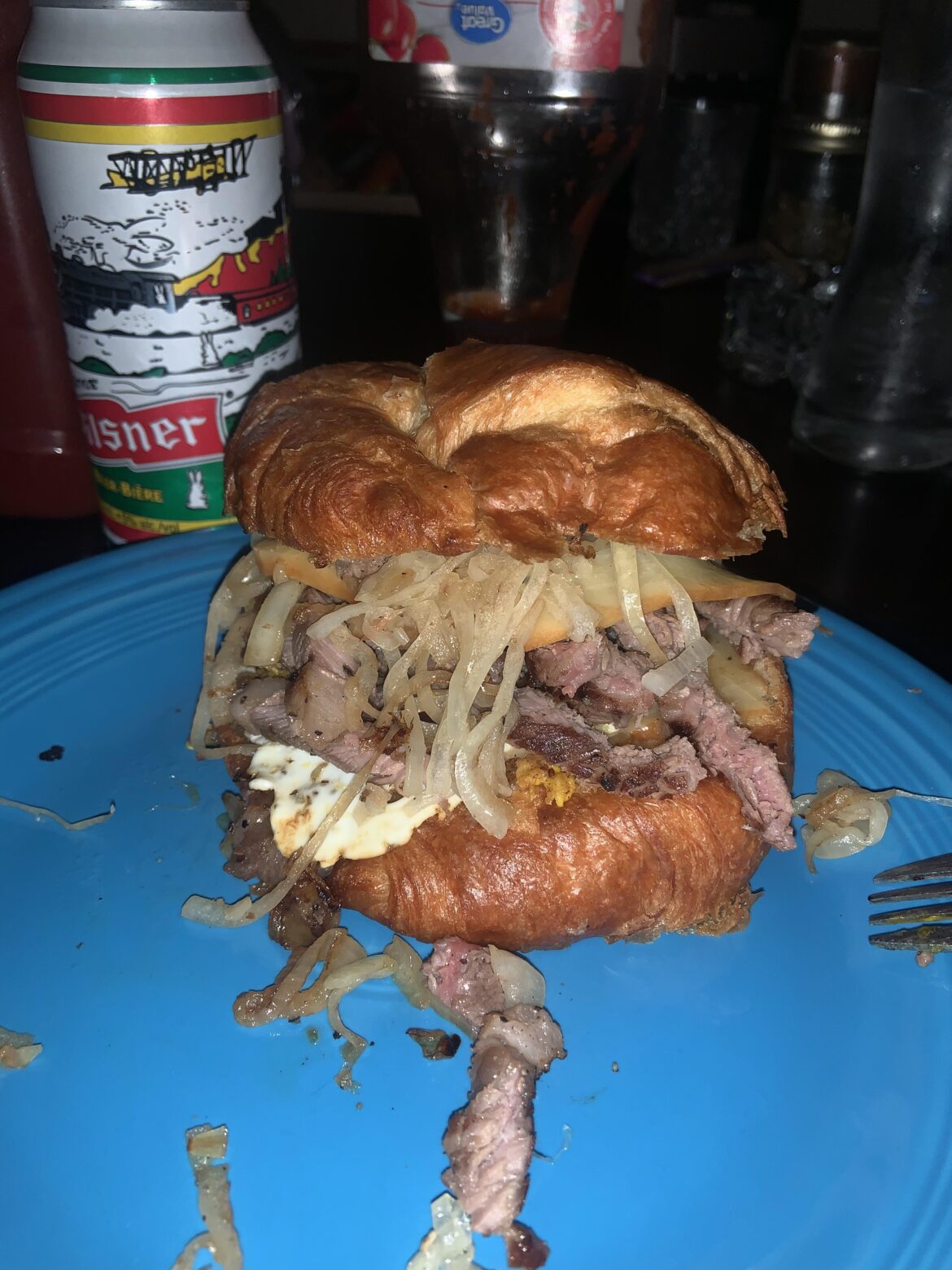 Steak, egg and fried onions on a croissant with smoked cheddar.