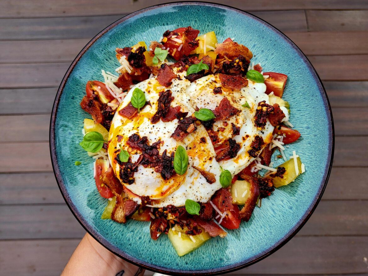 breakfast: crumbled bacon, chopped tomato and parmesan topped with over-easy eggs, chili crisp & basil.