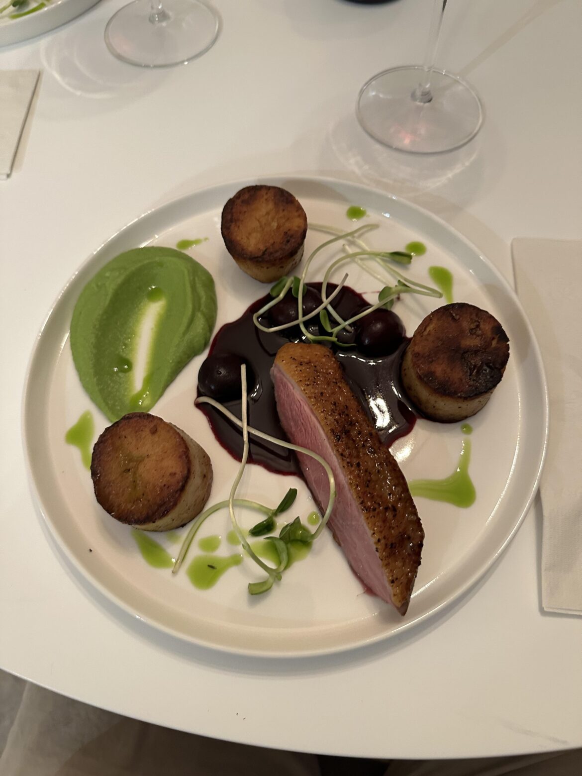 Sous vide duck breast with fondant potatoes, pea purée, cherry port sauce and parsley oil