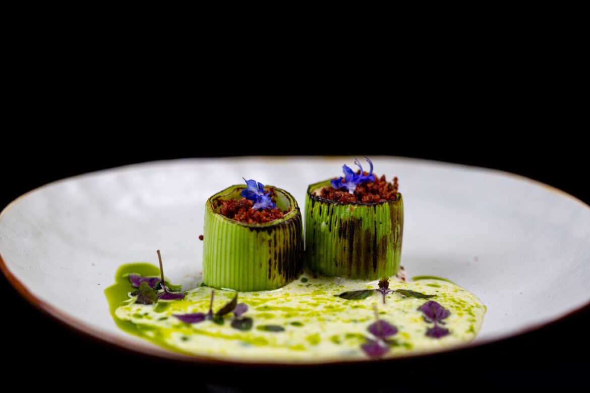Charred leek filled with smoked miso hollandaise foam, bacon crumb and soubise with wild garlic and parsley oil