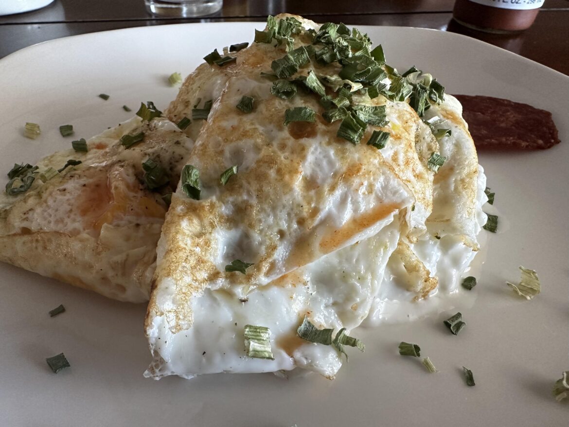 A Delightful concoction of Fried eggs with sprinkles of onion, on top of cottage cheese w/ side of turkey bacon