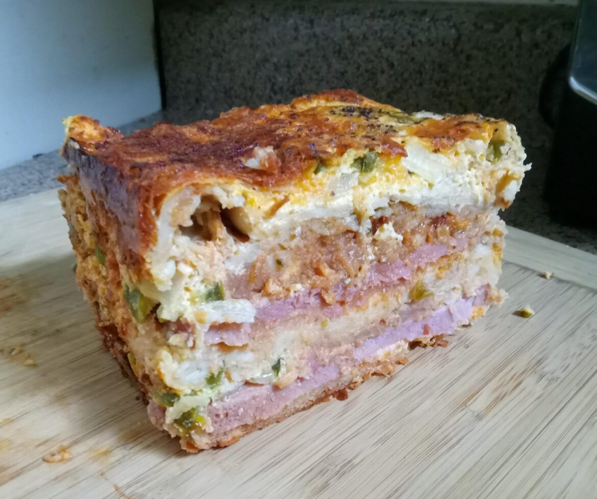 SOUTHWESTERN SCORCHER BREAKFAST CASSAROLE: Eggs, habanero and serrano peppers, slabs of smoked ham, refried beans, onions, cilantro, hot nacho style jalapenos, shredded potatoes, sharp cheddar & Carolina Reaper cheese all stacked with white corn tortillas.