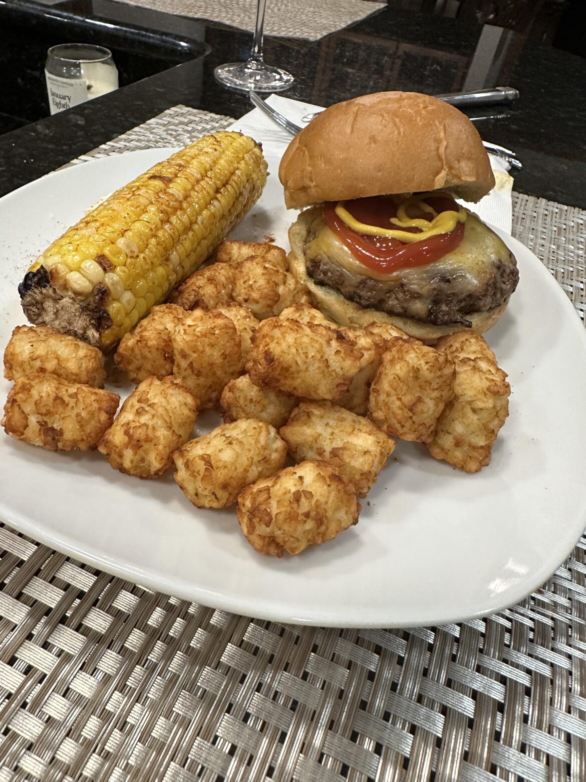 Mexican 3 cheese burger on brioche bun with tatertots and corn on the cob