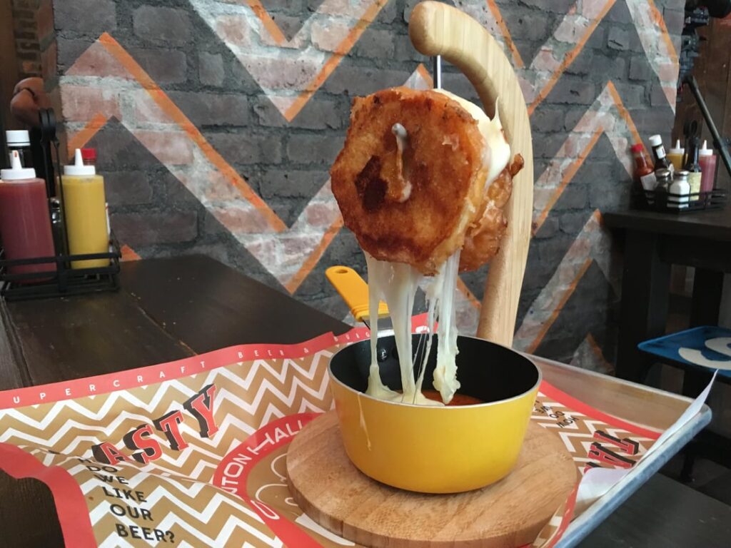 A Glazed Doughnut Grilled Cheese on a Banana Hanger (hanging over tomato soup) - Clinton Hall in Bronx, NYC