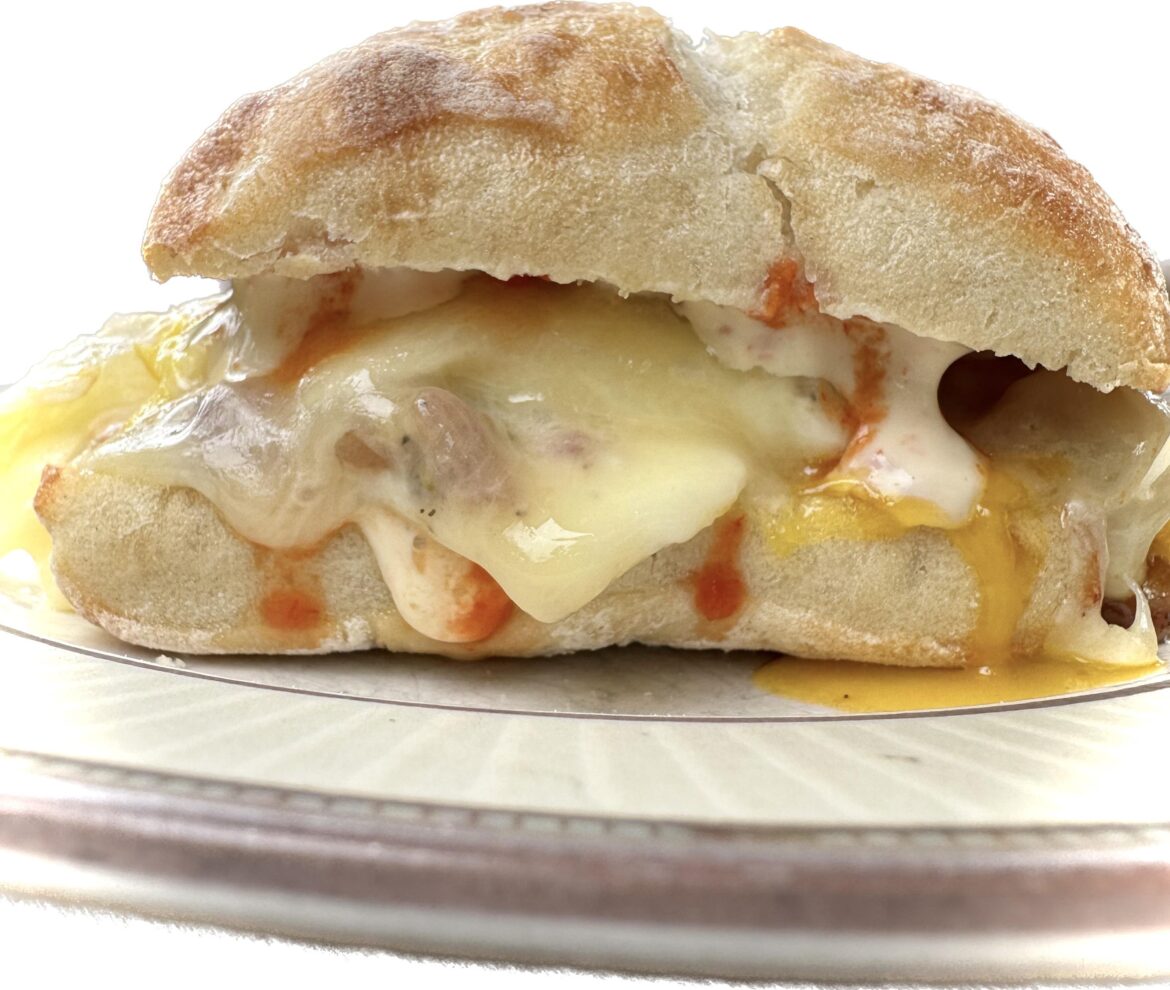 Fried egg and cheese with bacon and Texas hot sauce and creamy Baja on a crusty roll