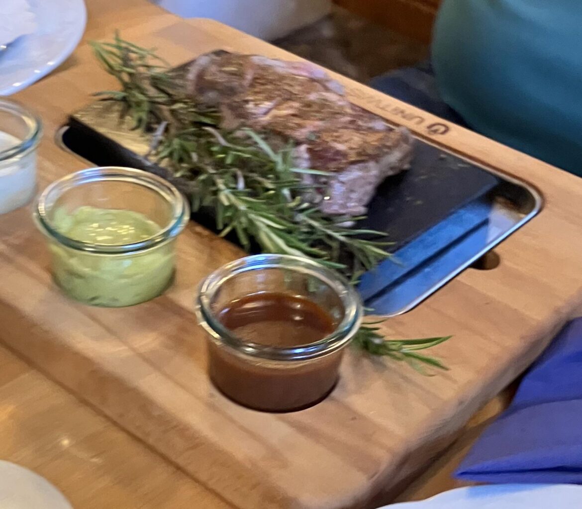 Steak on a hot stone on a wooden board with a rosemary tree