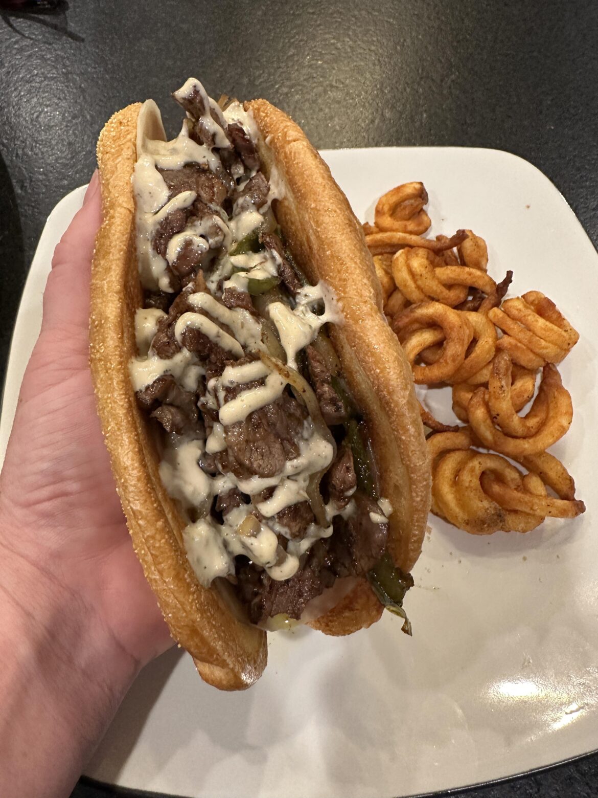 Steak sandwich with a bunch of garlic aioli, provolone, peppers and onions