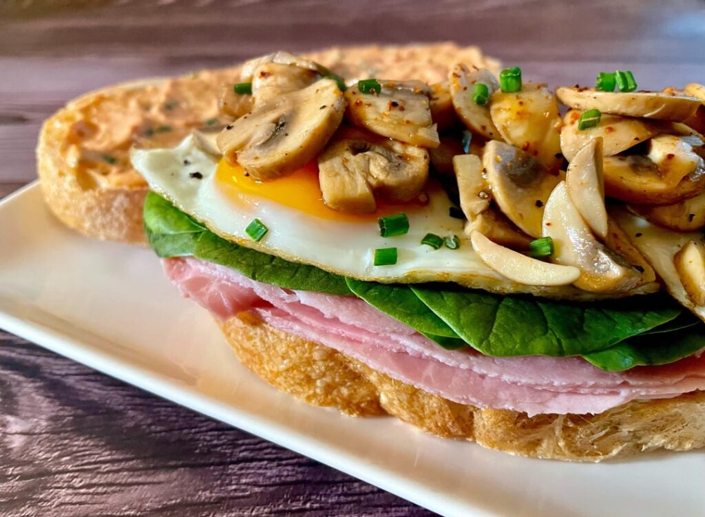 Eat-at-home messy sandwich with prosciutto cotto, baby spinach, fried eggs and mushrooms.