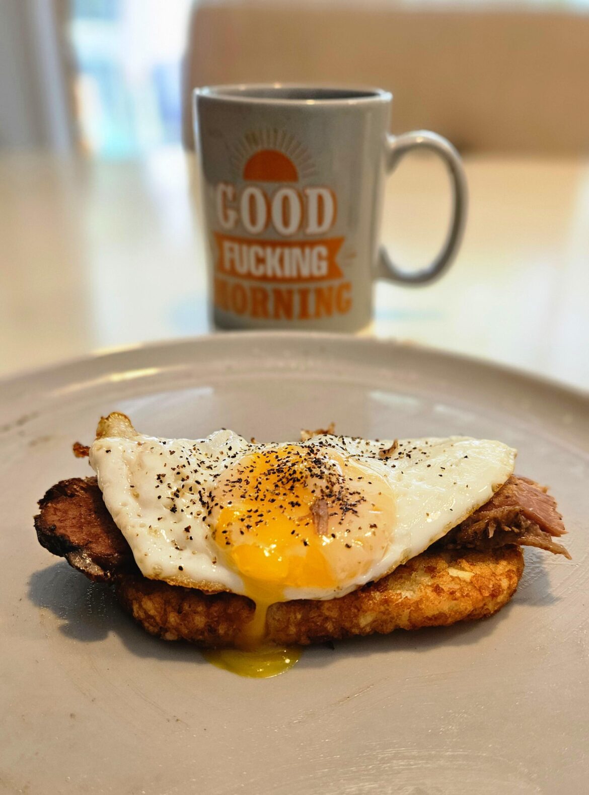 Hashbrown and a slice of smoked brisket with an egg on it.