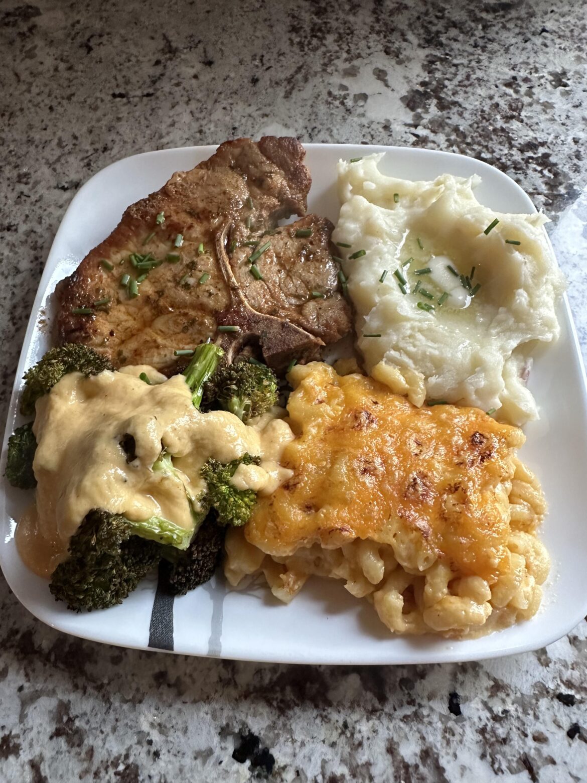 Pork Chop, Mashed Potatoes, Baked Macaroni and Cheese, and Broccoli with Cheese Sauce.