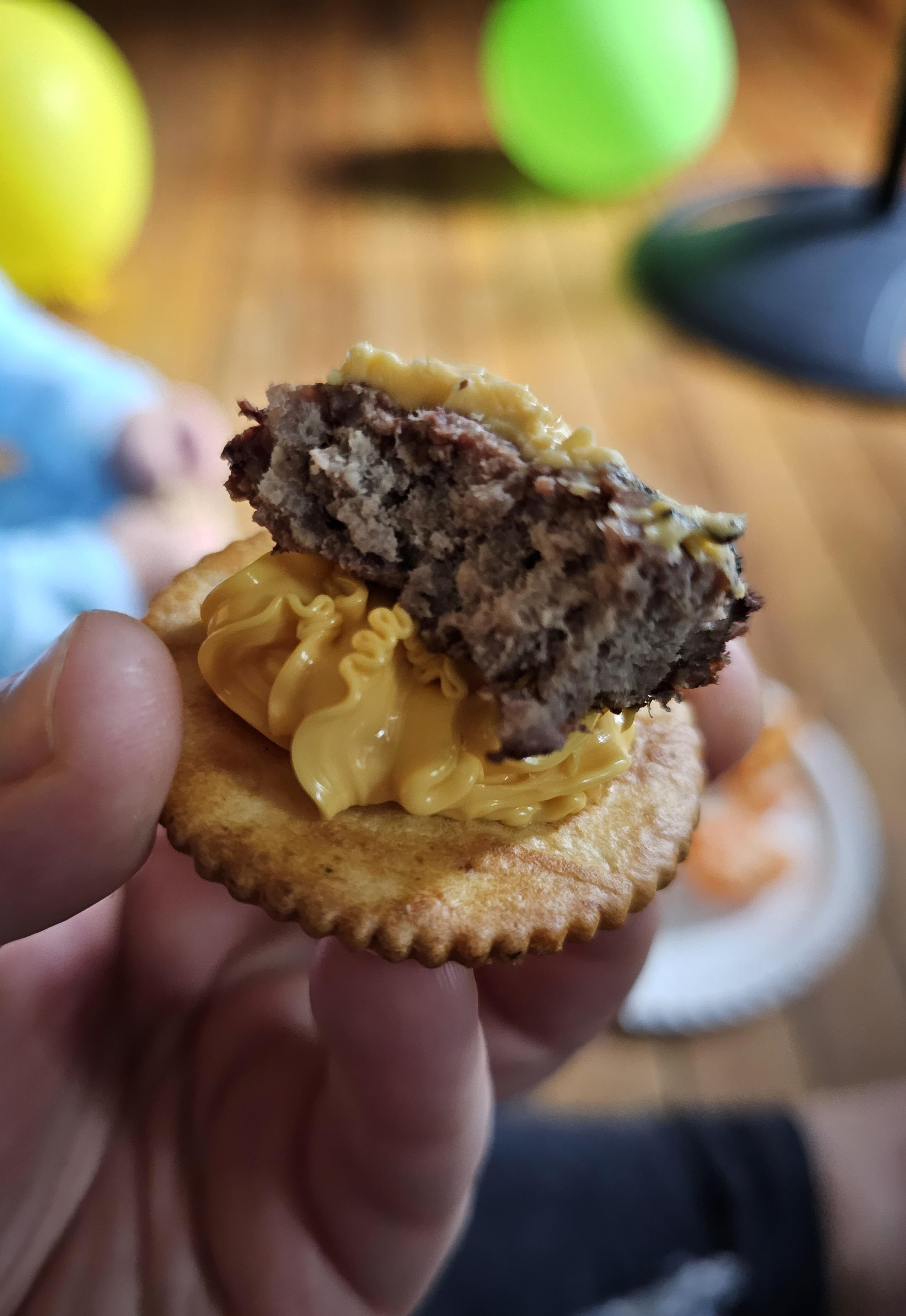 Veggie flavored Ritz cracker with squeeze cheese and a piece of